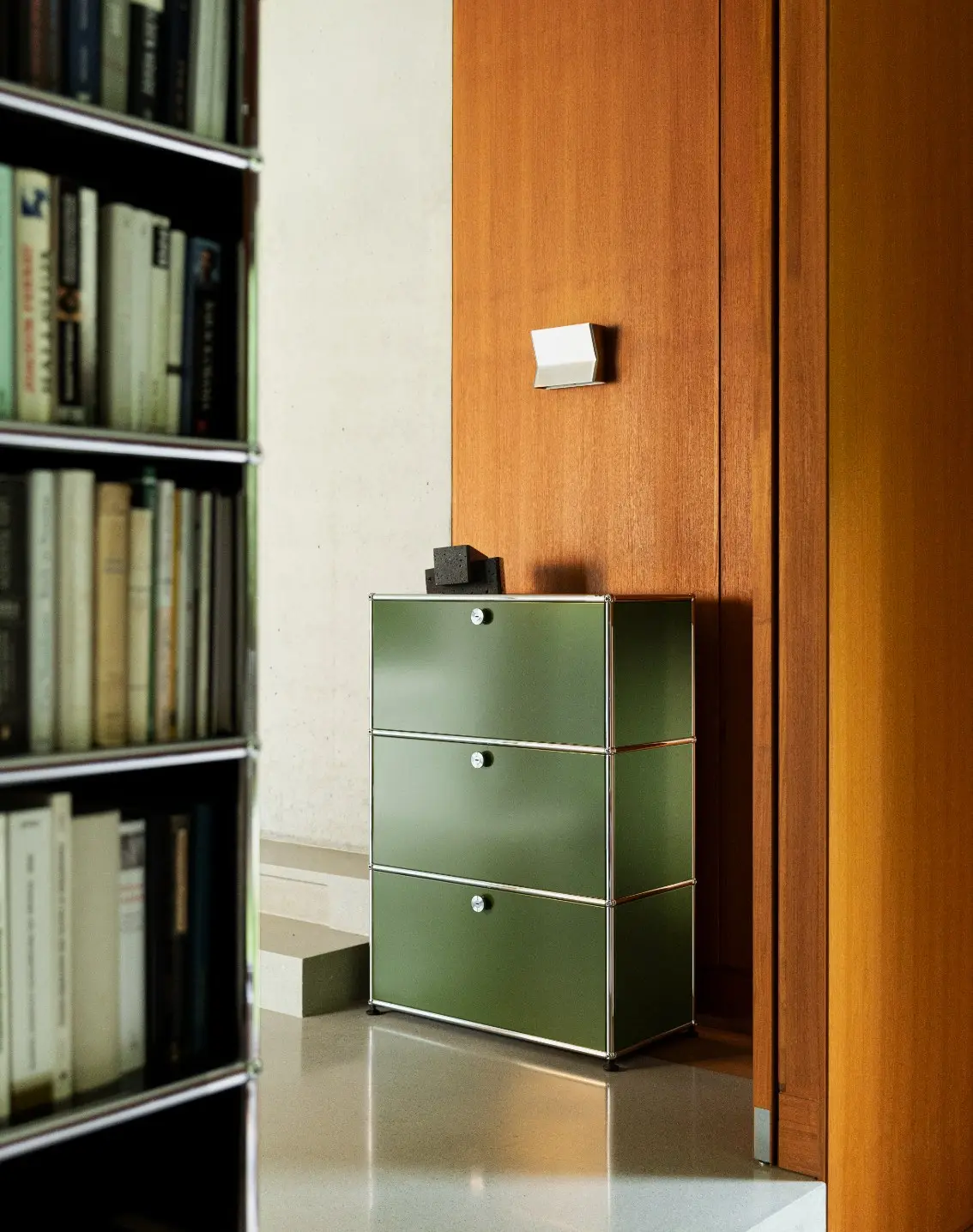 Grünes USM-Haller-Sideboard vor einem gefüllten Bücherregal